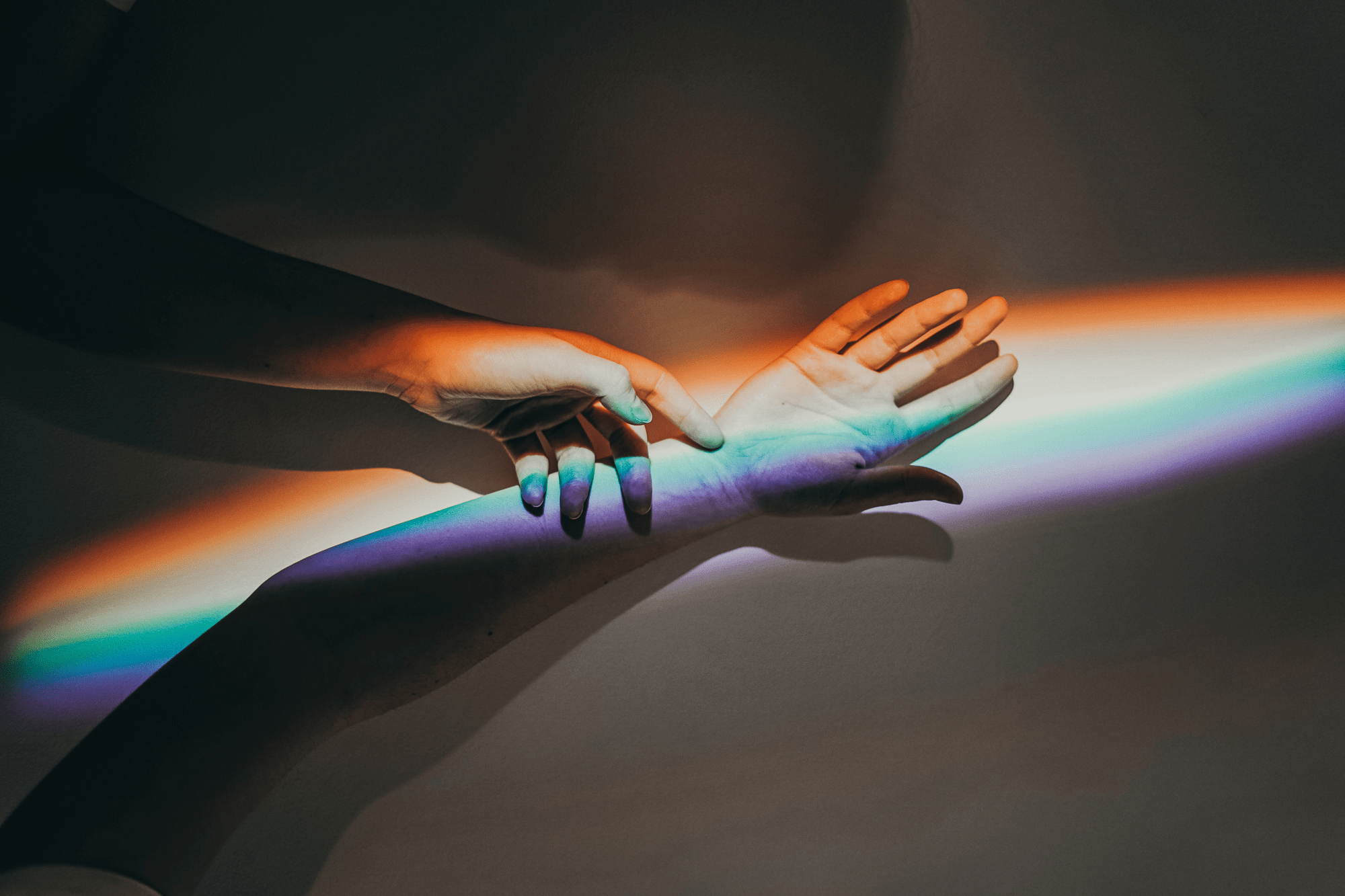 Pride bei Braintower, zwei Hände berühren sich im Regenbogenlicht